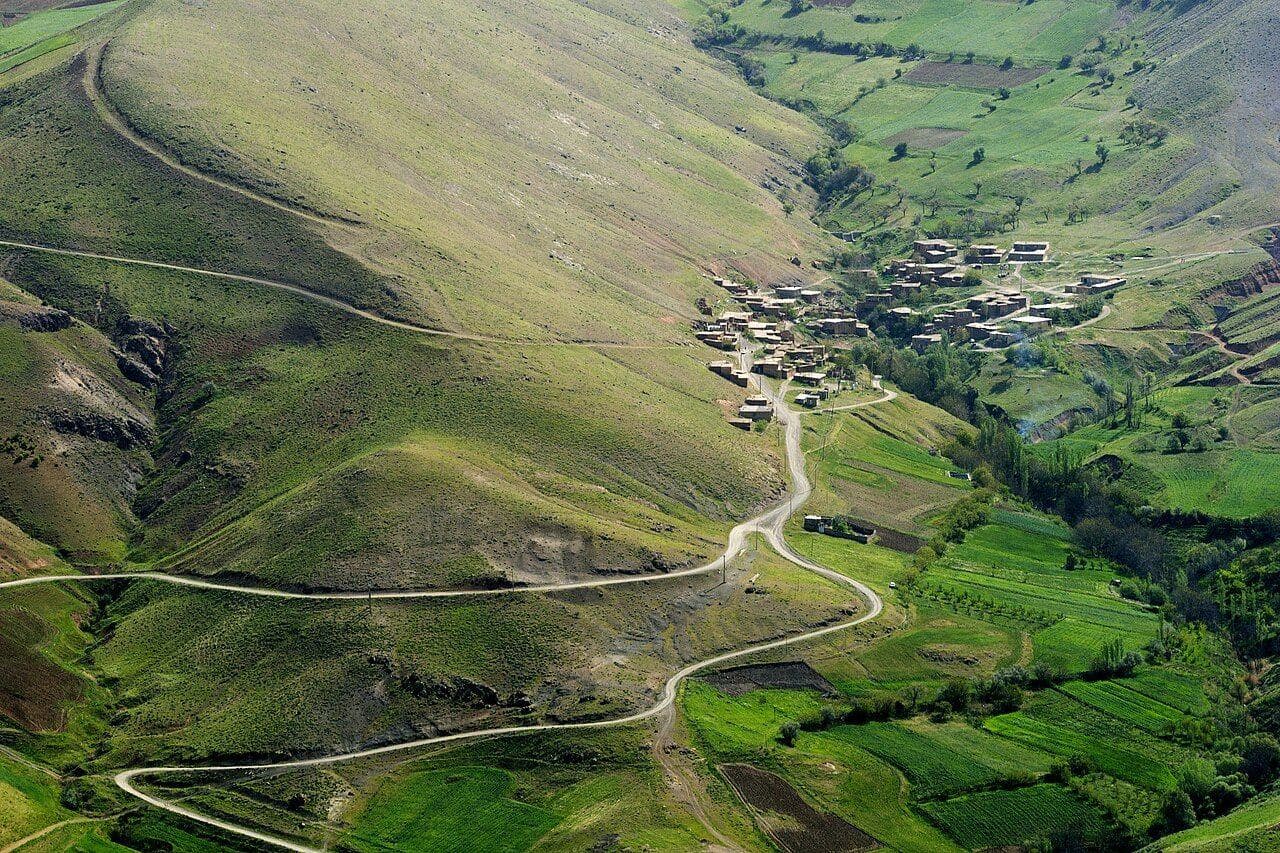 ڕێگایەکی پێچاوپێچ بەرەو گوندێک لە ناو کێڵگەکان